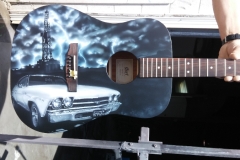 What kind of music do you play on a guitar decorated with lightning, oil derrek and cool car?